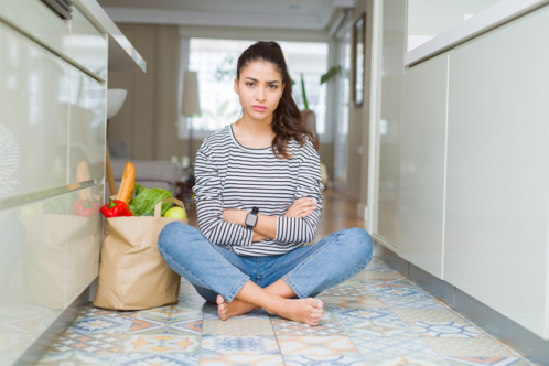 Young,Woman,Sitting,On,The,Kitchen,Floor,With,A,Paper